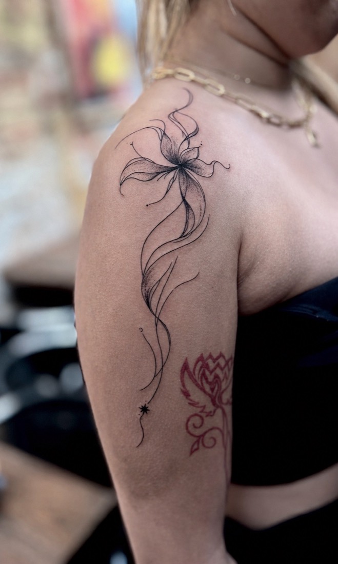 Fine line lily with trailing stems down a shoulder, by Tuba at THRONE Northampton